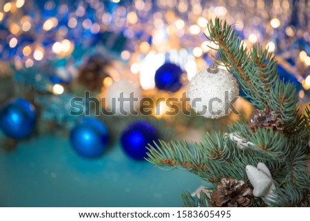 Christmas composition white Christmas ball on a spruce branch. background made of bokeh lights. postcard. space for text . the 2020 colors are white and blue.