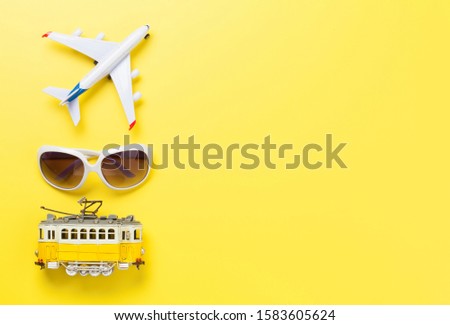Travel concept backdrop with airplane toy, tram and sunglasses. Top view flat lay with copy space