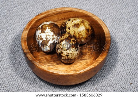 Quail eggs in a round wooden bowl on canvas, close-up, macro. Eggshell stains. Spotted pattern on the eggs. Dietary healthy foods. Egg. Eggs on burlap. 