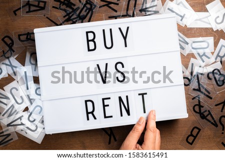 Hand insert the plastic alphabets into the sliding lightbox sign as Buy VS Rent concept