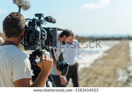 videographer with tripod camera in documentary film shooting  Royalty-Free Stock Photo #1583654923