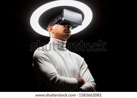 future technology, augmented reality and people concept - man in virtual reality headset or vr glasses under white illumination over black background