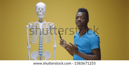 Medium shot of young man explaining human anatomy against yellow background