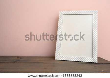 White blank mock up of photo frame on the light background. Home interior, wooden shelf near pink wall close-up