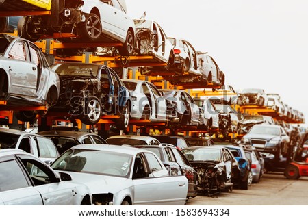 Damaged cars waiting in a scrapyard to be recycled or used for spare part Royalty-Free Stock Photo #1583694334