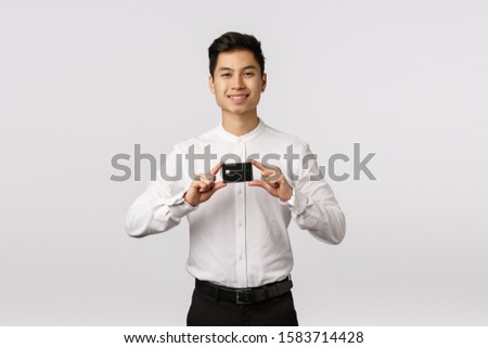 Businessman got new credit card. Satisfied good-looking asian young man holding bank card and smiling pleased, pay with cashback, got bonuses, introduce finance product, white background Royalty-Free Stock Photo #1583714428