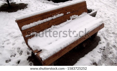 wooden bench covered with snow in the daytime