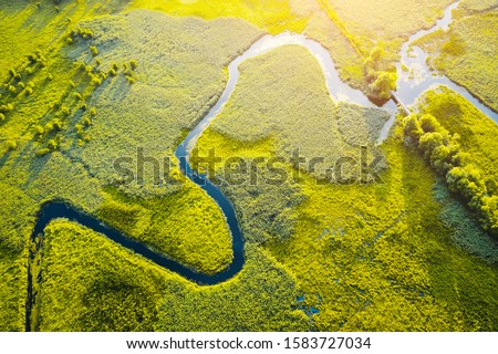 Aerial drone view of winding river in green field. Lush wetlands of bird's eye view. Location place countryside of Ukraine, Europe. Textural image of drone photography. Discover the beauty of earth.