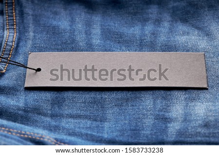 horizontal price sale tag on blue denim jeans cloth. mockup for design or decor. copy space. 