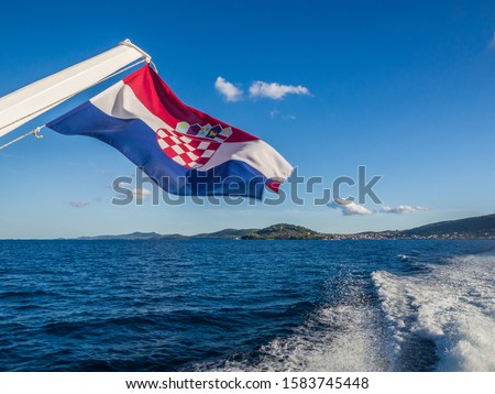Croatian flag on the boat captured during the boat trip from Zadar city center to Preko island. Zadar regoin, Croatia. Royalty-Free Stock Photo #1583745448