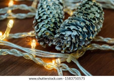 Fir cones and Christmas garlands on a background of dark wood. Copy space. Christmas card concept. Top view, close up.