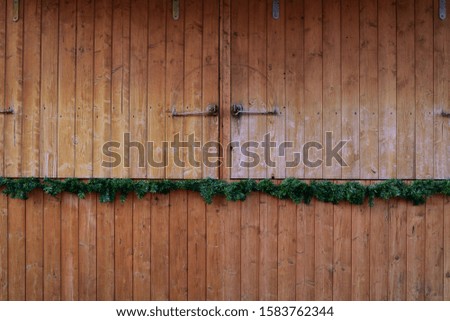 A closed wooden flap, which is weathered, with decorative plastic action fir branches as background and place for text