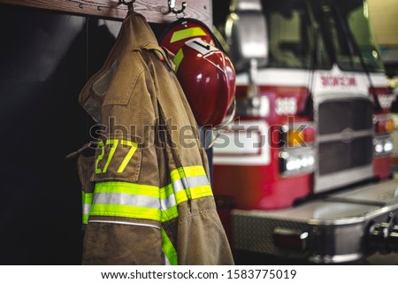 Firefighter protection helmet and jacket in the firehouse Royalty-Free Stock Photo #1583775019