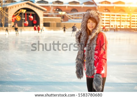 young happy woman in hat skating on ice on the street