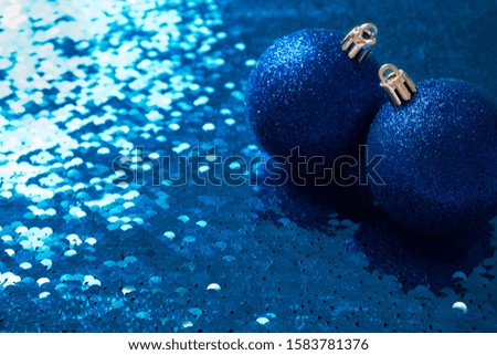 blue shiny Christmas toys decoration balls on a sparkling blue sequin background. Christmas New Year background with place for text.