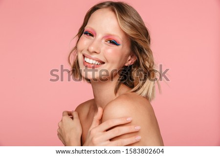 Close up beauty portrait of an attractive smiling young blonde topless woman with bright makeup standing isolated over pink background, posing Royalty-Free Stock Photo #1583802604
