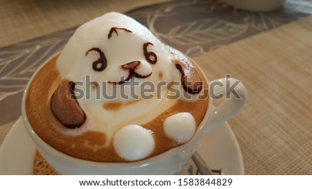A view of 3D coffee art with cute dog cartoon. Coffee artist or barista whipping up 3D coffee foam characters that pop out of the mug. It is a super creative latte foam artworks.