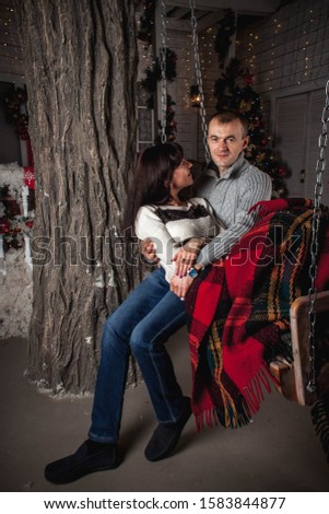 couple in love on Christmas eve sitting on a swing under a blanket