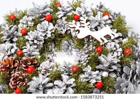Christmas wreath of cones painted in gray and green needles with decorative deer silhouette, close up details