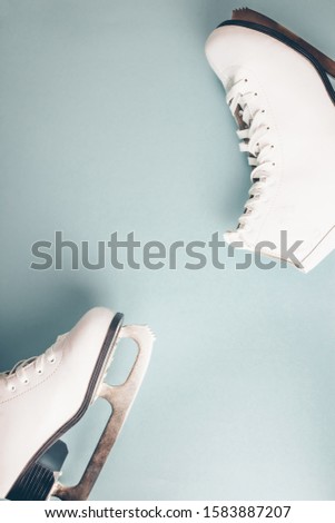White figure ice skates on light blue background. Winter holidays concept. Top view. Flat lay