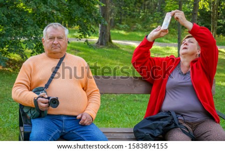Mature tourists walk and take pictures in the Park at the waterfall on a Sunny day