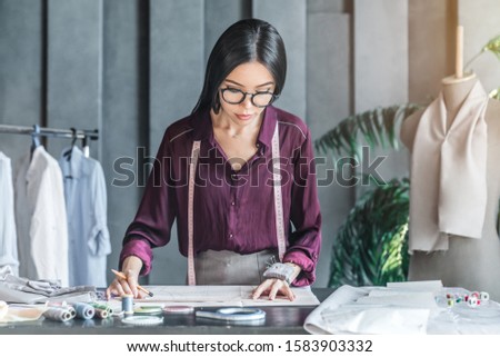 Asian woman fashion designer working on her model in showroom