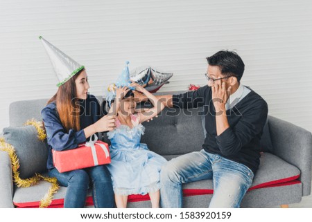 Father, mother and daughter are celebrating Christmas. Christmas hat and a gift for each other. Concept Asian family happiness time.