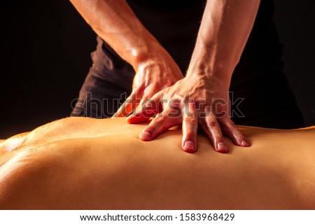 young indian woman lying on the table and getting ayurvedic massage with organic oil or honeyed in dark room.massagist male pouring out client back . Royalty-Free Stock Photo #1583968429