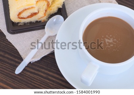 Hot coffee in a white cup and orange flavored cake
