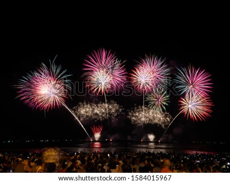 Many people are excited and have fun watching the fireworks show and using a smartphone to take pictures.