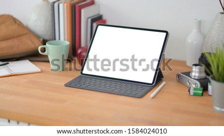 Cropped shot of comfortable office room with blank screen digital tablet on wooden table with office supplies 