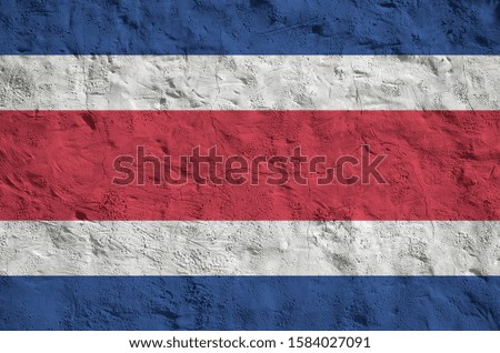 Costa Rica flag depicted in bright paint colors on old relief plastering wall. Textured banner on rough background