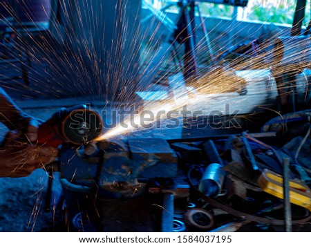 Worker grinding or  cutting  metal  with cutting machine. There is a lot of beautiful sparks and smoke .