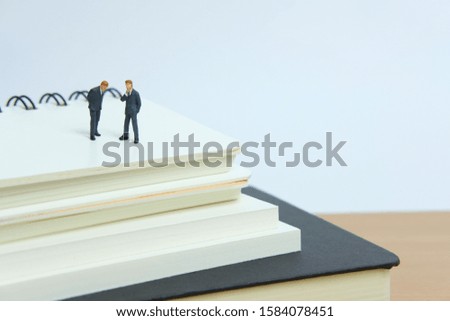 Miniature business concept - businessman make an agreement above book