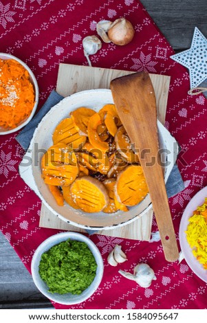 [object Object]Grilled baked pumpkin slices in pan on red Christmas tablecloth background.