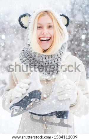 Beauty Joyful Girl having fun in winter park. Beautiful smiling young woman in warm clothing with ice skates. Winter landscape background. Winter young woman portrait