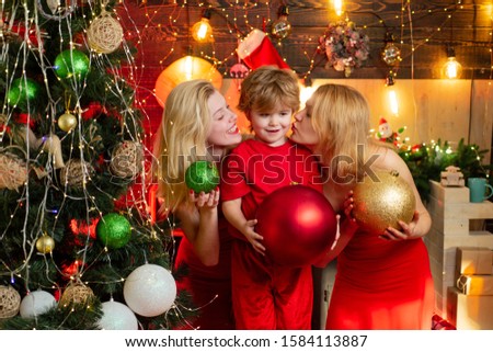 Girls are kissing their lovely little brother by the Christmas tree. Christmas decoration. Happy new Year