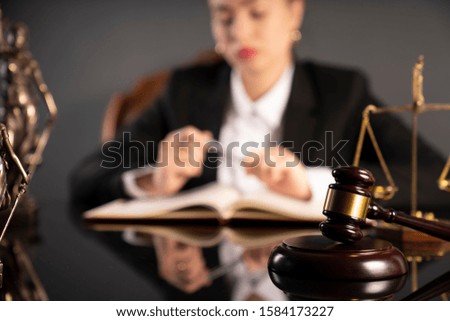 Young female judge working in courtroom. Law and justice symbols on the table.