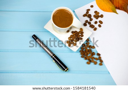 autumn leaves smell coffee and drink a cup of turkish coffee
Top view  autumn composition a wooden blue background for design. White paper beautiful writing pen dried tree leaves 