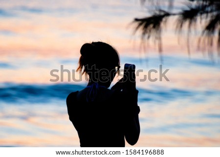 Silhouette of lady taking a picture with mobile phone.