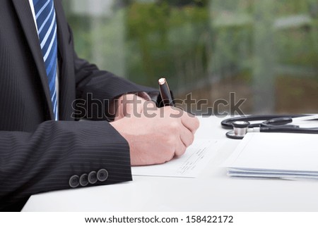 A doctor doing some paperwork in his consulting room
