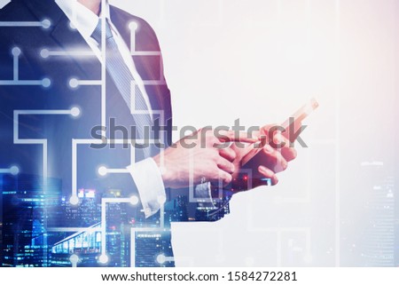Unrecognizable businessman working with smartphone in night city with double exposure of digital maze. Concept of technology and challenging task. Toned image