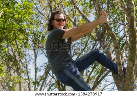 A blond and caucasian man posing for photos and enjoying the sun and nature in spring afternoon in the Brazilian countryside. Photographic model in outdoor and rural photo shoot.