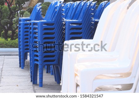 Many blue plastic chairs  Stacked orderly  And with sunlight shining