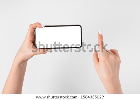 Female hand holding and touching on mobile smartphone with white screen. Isolated on white. Photo template for any images on mobile phone display Layout with easily removable phone monitor background