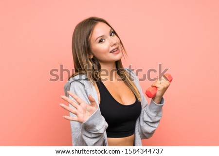 Teenager sport girl making weightlifting over isolated pink background saluting with hand with happy expression