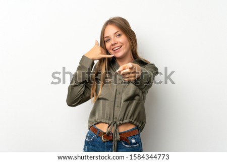 Lithuanian blonde girl over isolated white background making phone gesture and pointing front