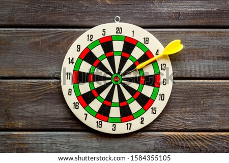 Darts game - simple sport for lesure time. Dartboard and arrows or dart on dark wooden background top view copy space