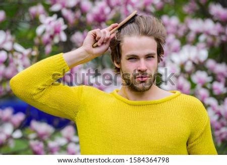 Floral cosmetics concept. Hipster enjoy blossom aroma. Spring beauty. Hairdo styling. Man flowers background defocused. Botany nature. Male beauty. Hair care and beauty. Unshaven man magnolia bloom.
