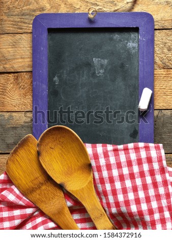 Restaurant menu on a chalk board with a kitchen cloth on a wooden table. High resolution photography ideal as a background for restaurants or chefs. Empty space to enter text, top view.